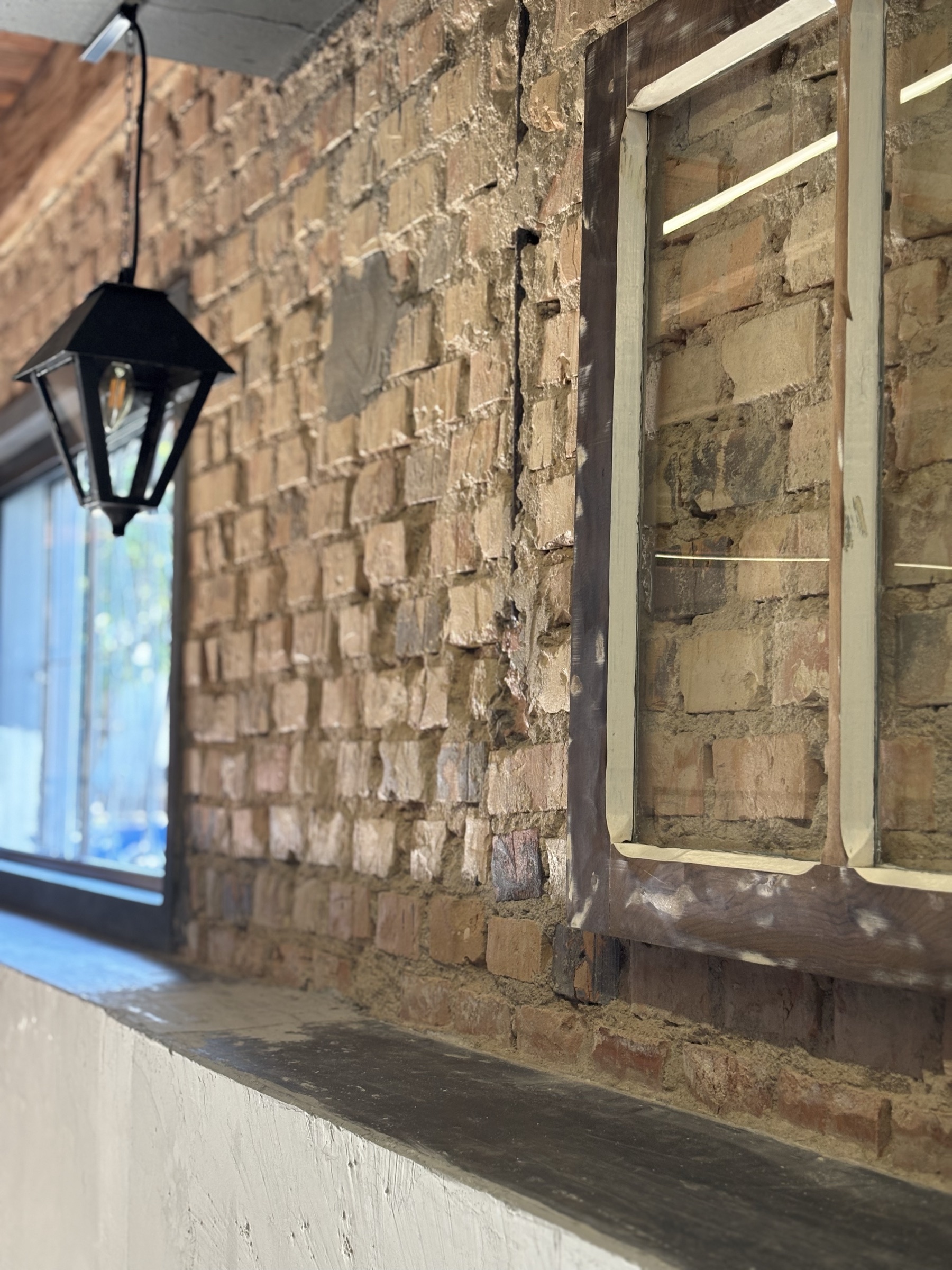 Detalhe da parede de tijolos e luminária do salão